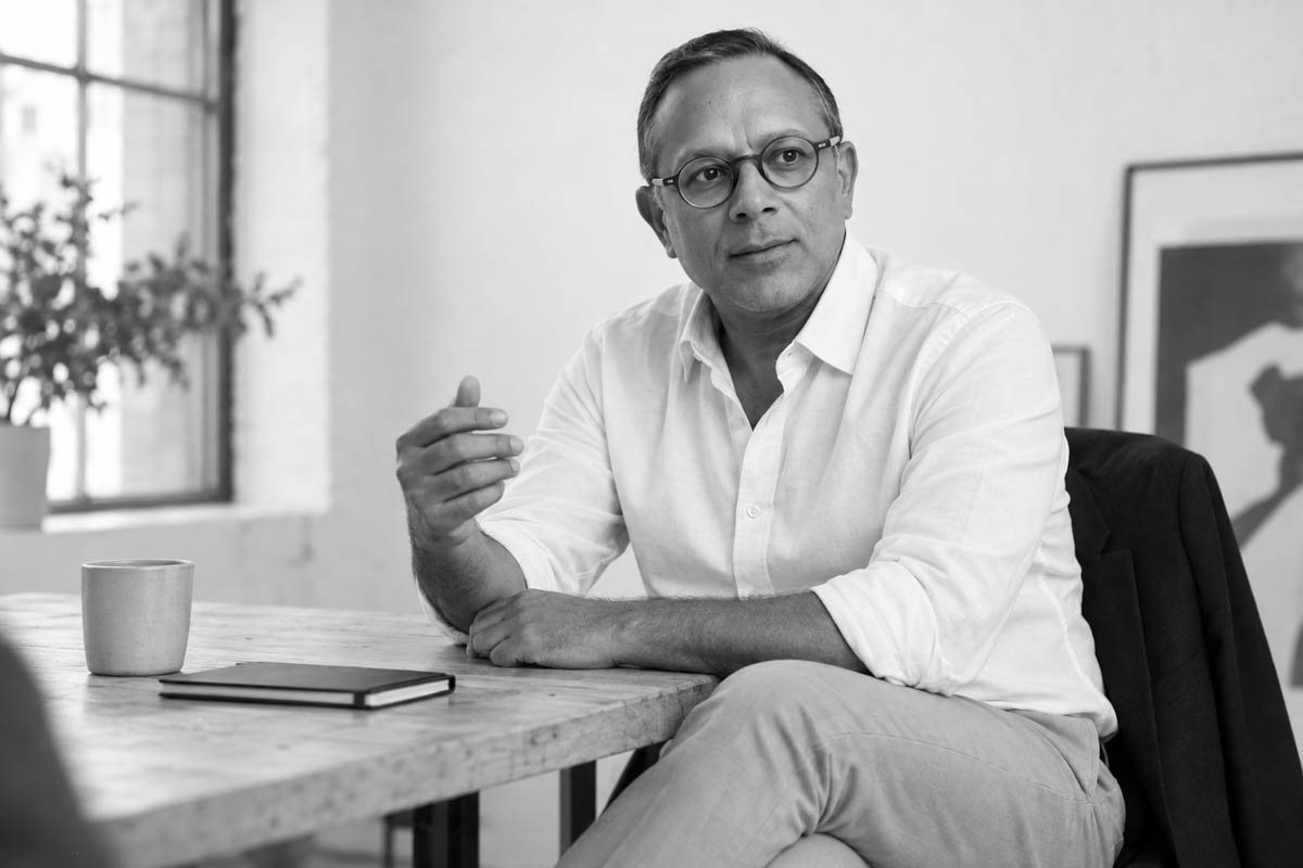 Mihir Taneja seated at a table mid-conversation, gesturing