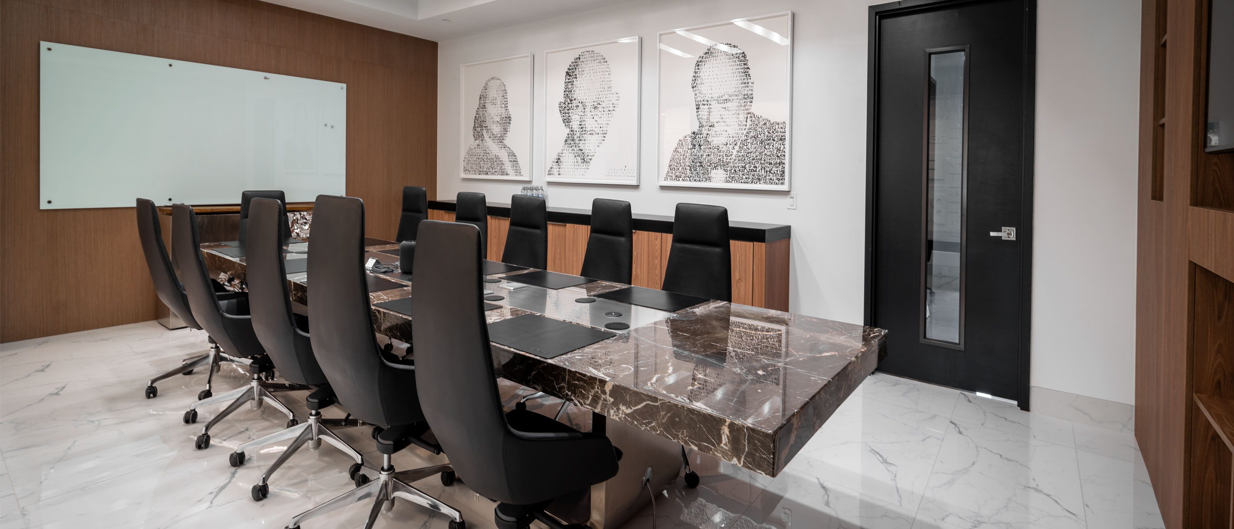 An empty boardroom with a marble table and leather chairs